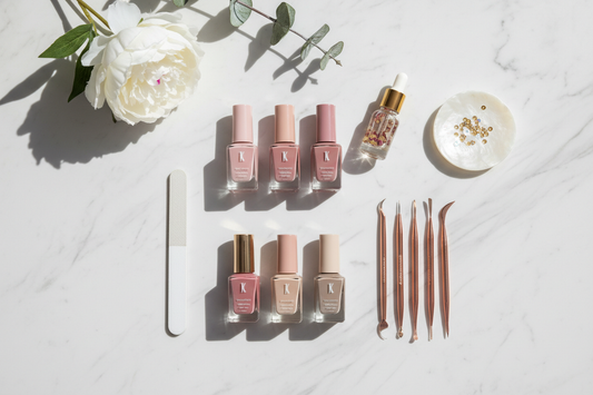 "Flat lay of nail care products including pink nail polish bottles, cuticle oil, and nail art tools on a white marble background, representing La Glow's nail care guide"
